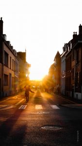 Au programme des voies off 2017.Un Carnavaleu à Dunkerque dansant en traversant un passage pieton. Le soleil.se couche