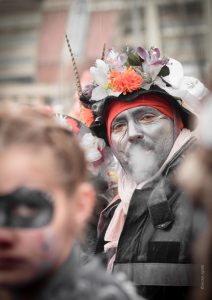 Carnaval de Dunkerque, un portrait de carnavaleux crachant sa fumée un femme floue au premier plan.