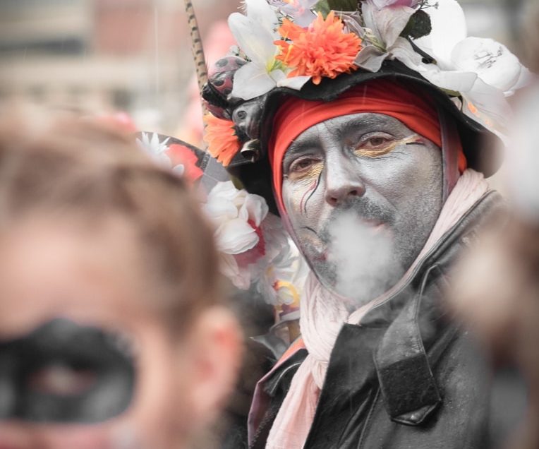Carnaval de Dunkerque, un portrait de carnavaleux crachant sa fumée un femme floue au premier plan.