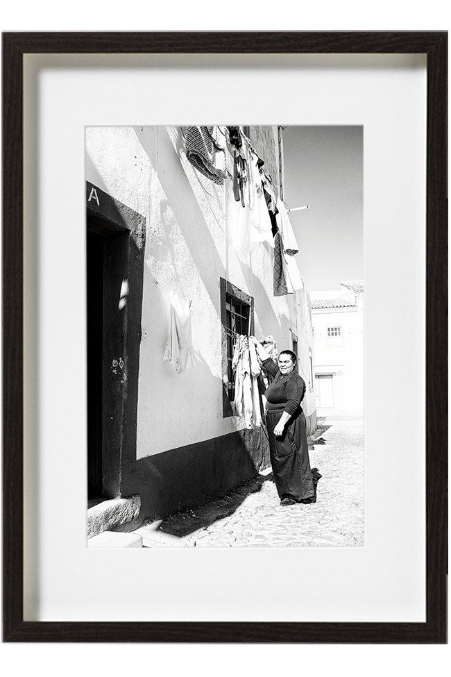 A Lisbonne, au Portugal, une femme toute vêtue de noir accroche son linge, dehors, sur l'étendoir de sa fenêtre.