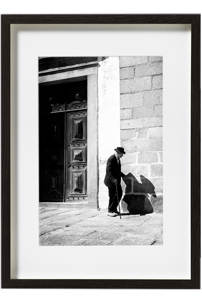 A Evora, au Portugal, un vieil homme tout vêtu de noir, chapeau sur la tête, avance tout doucement le long d'un mur à l'aide de sa canne.