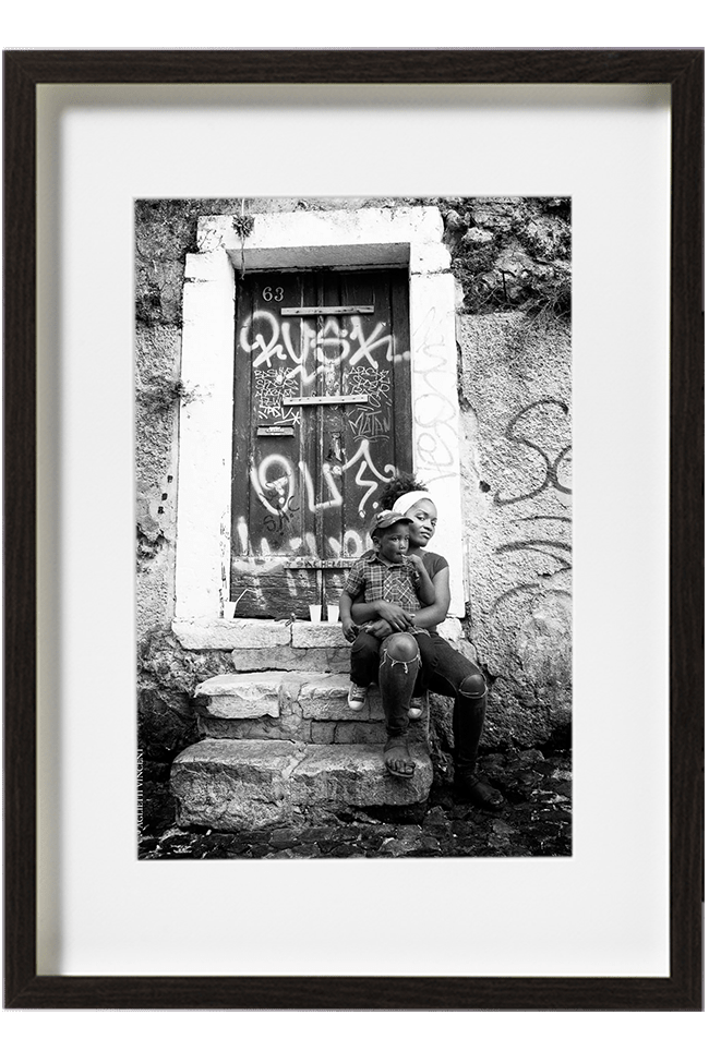 A Lisbonne, au Portugal, dans le quartier de la Mouraria, une jeune femme est assise sur les marches avec son enfant sur les genoux.