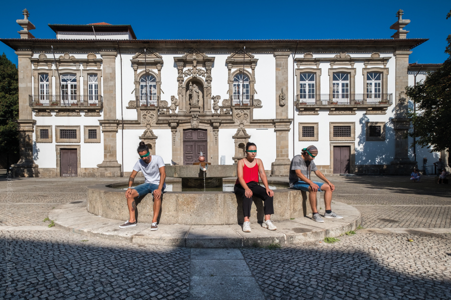 Trois jeunes posent assis sur la fontaine les yeux bandés.Derrière eux la mairie de Guimaraes. Photo pour l'exposition Guimaraes, Aqui Nasceu Portugal de Vincent Aglietti et Vincenzo Cirillo.