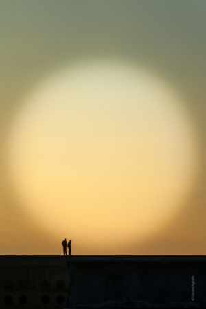 Contre-Jour. Deux hommes sur une jetée observent l'horizon.