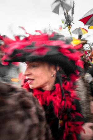 Au Féminin.Une femme coiffée d'un grand chapeau se retournant dans la foule du carnaval.