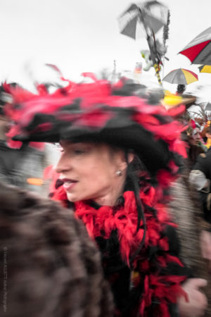 Au F&eacute;minin.Une femme coiff&eacute;e d'un grand chapeau se retournant dans la foule du carnaval..