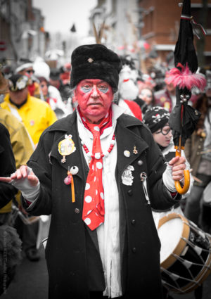 La Mesure du Temps.Un homme, vieux carnavaleux battant la mesure avec son parapluie et précédant la bande.