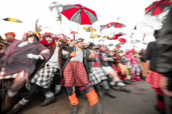 Première Ligne. La première ligne du carnaval tenant leur berguenard et donnant la sensation de s'écrouler dans un flou artistique.