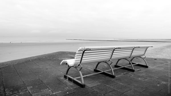 Face à la Mer.Un banc vide face a la mer du nord, la plage est vide et le ciel se couvre.