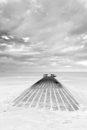 La Jetée Engloutie.Sur la plage de knokke le zoute la mondaine, une jetée rejoint l'horizon sous un ciel orageux.