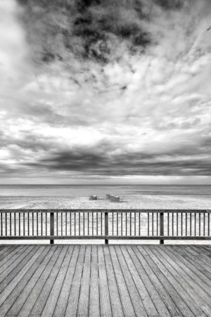 Automne sur Mer.Un terrasse en bois surplombant la plage, sur le sable les paravents et accessoires s'empilent.