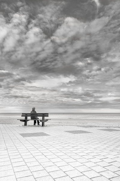 En Attendant. En Belgique a Knokke-Le-Zoute une femme assise sur un banc face a la mer du Nord
