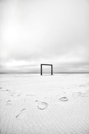 Tableau Flamand. Un portique formant un cadre naturel sur la plage de Knokke, met en valeur un voilier passant au même moment.