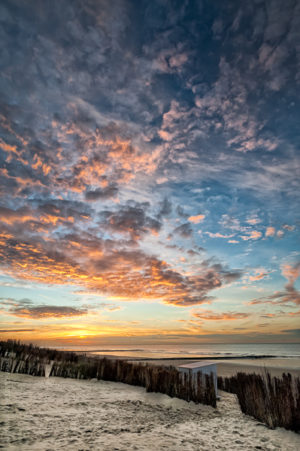 Ciel de Traine.Un coucher de soleil sur la mer du nord, une plage ,une cabine et des canisses contemplent ce spectacle.