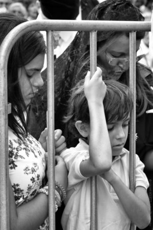 Derri&egrave;re les Grilles. De Saint-Antoine &agrave; Fatima, une famille derri&egrave;re les barri&egrave;res prie devant le passage de la procession. .