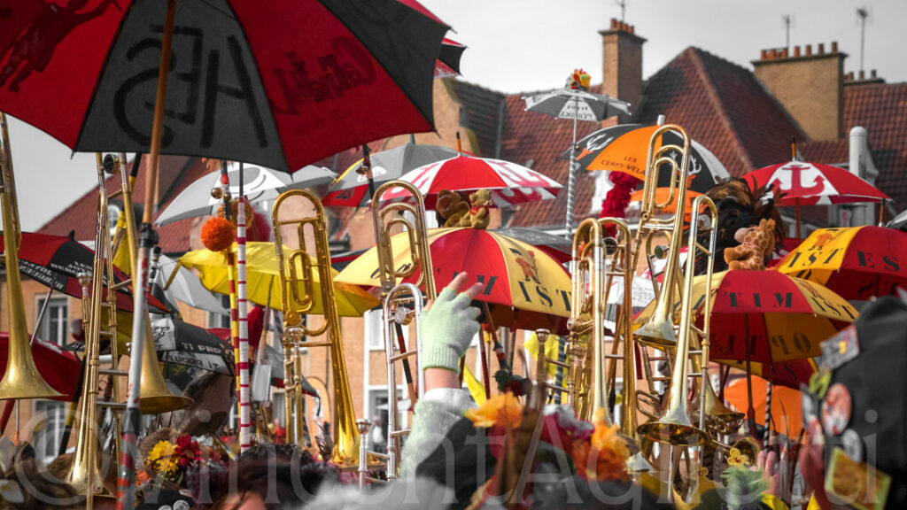Personnages déguisés tenant à bout de bras leurs instruments de musique pendant le carnaval de Dunkerque à Bergues