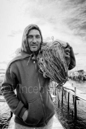 Portrait d'Alvaro, marin portugais portant un filet de pêche dans la baie de Troia au Portugal.