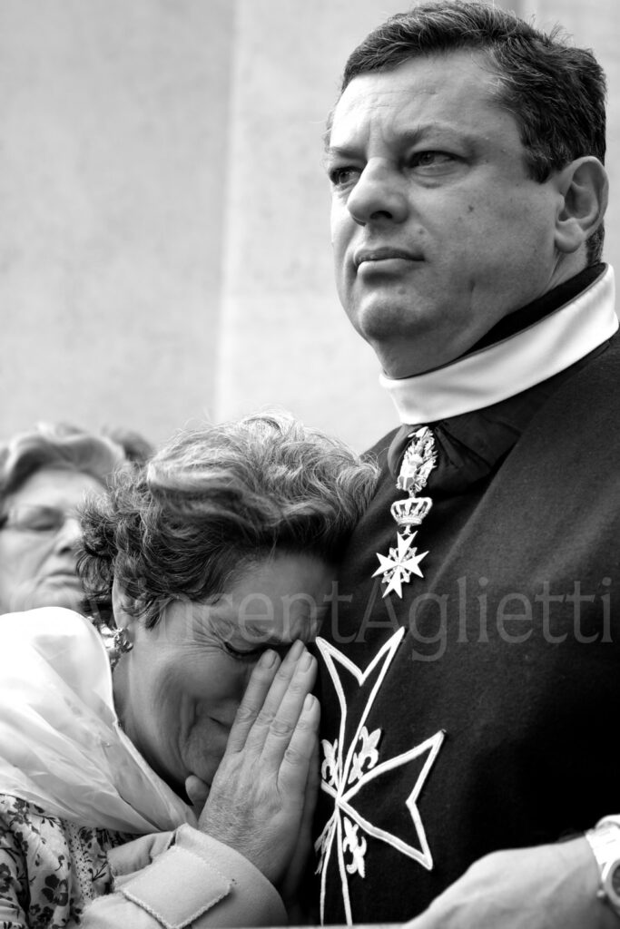 Femme en prière trouvant du réconfort auprès d'un membre de la confrérie pendant la procession de Saint Antoine à Lisbonne.