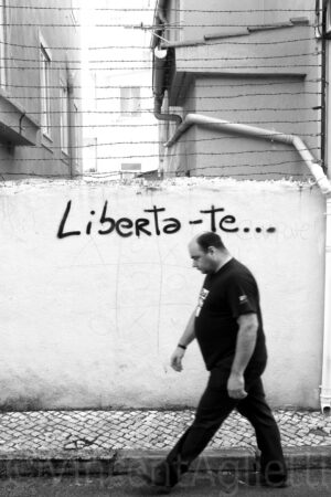 Passant devant un graffiti « Liberta-te » dans une rue de Lisbonne.