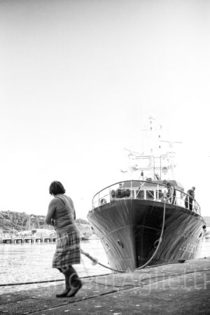 Dockeuse saisissant l'amarre d'un bateau entrant dans le port de Nazaré au Portugal.