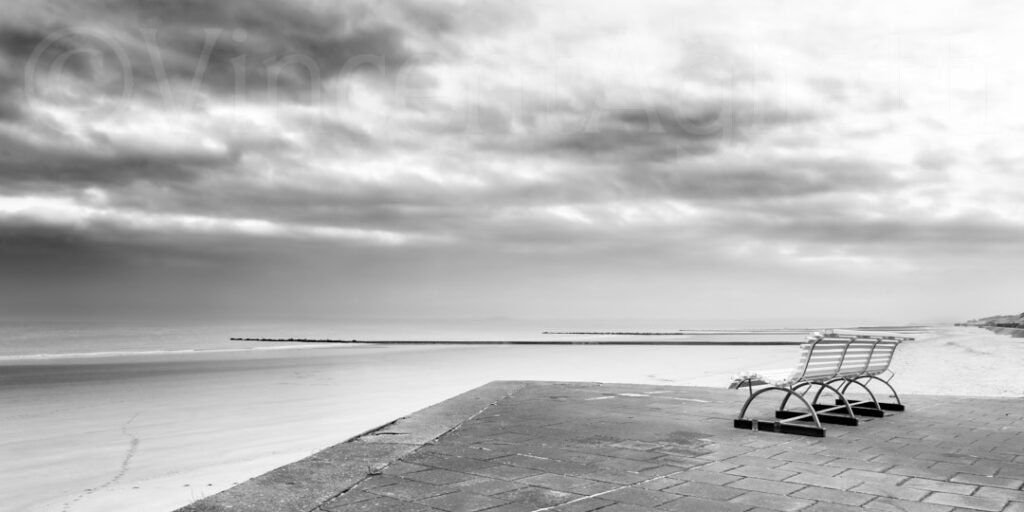 Banc vide face à la mer sur la plage d’Ostende en noir et blanc