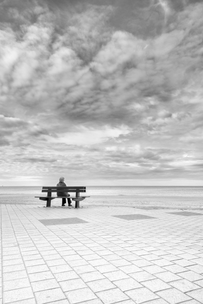 Personne assise seule sur un banc face à la mer du Nord sur la côte belge