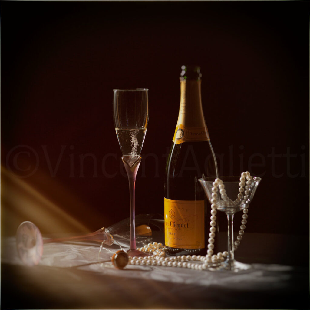 Bouteille de champagne, flûte et collier de perles photographiés sur fond sombre