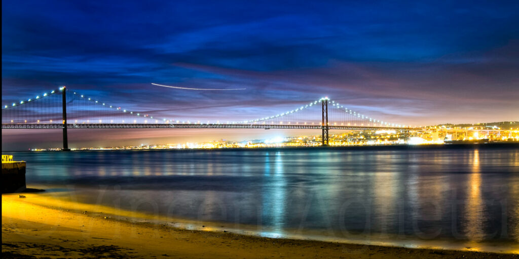 Pont du 25 Avril illuminé de nuit vu depuis la rive d’Almada face à Lisbonne
