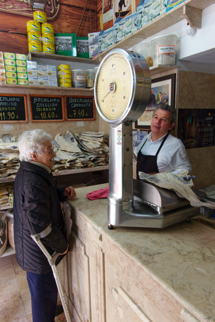 Cliente échangeant avec un marchand de bacalhau dans une boutique traditionnelle à Lisbonne