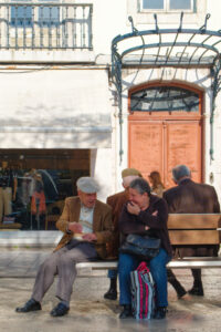 Homme âgé et femme assis sur un banc en conversation dans une rue de Lisbonne