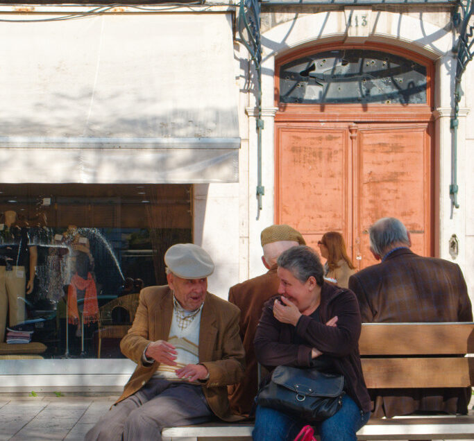 Homme âgé et femme assis sur un banc en conversation dans une rue de Lisbonne