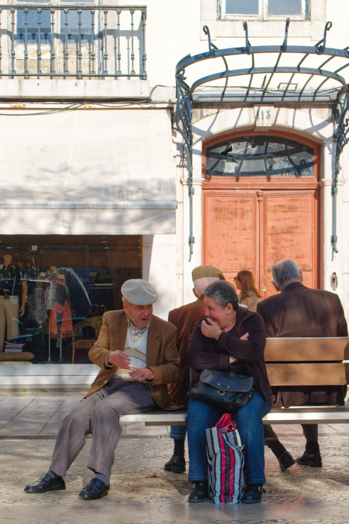 Homme âgé et femme assis sur un banc en conversation dans une rue de Lisbonne