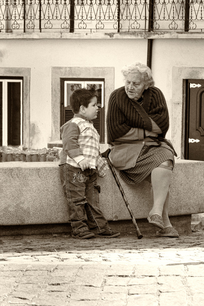 Femme âgée assise parlant avec un enfant dans une rue du Portugal