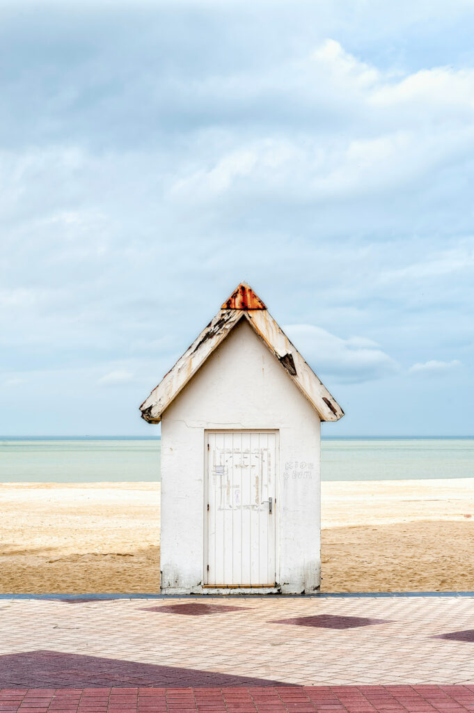 Cabine blanche sur la plage face à la mer sous un ciel bleu clair